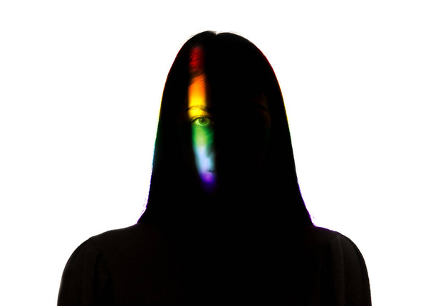 Dramatic portrait of a girl in the dark on white studio background with rainbow colored line - Photo, image