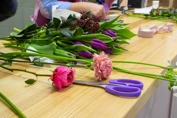 nůžky na stříhání květin leží na stole s květinami v květinářství - Fotografie, Obrázek