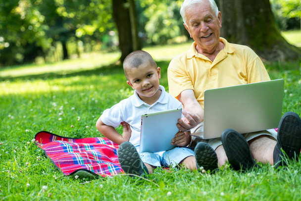 grandfather and child using tablet computer in park - Фото, зображення