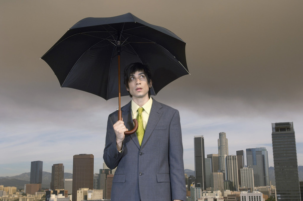 Businessman holding umbrella - Fotó, kép