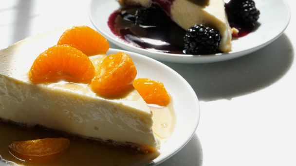 Kawałek domowego ciasta serowego z migdałową skórką z dodatkiem mandarynek z polewą z sosem pomarańczowym i kawałkiem jeżyny  - Zdjęcie, obraz
