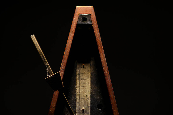 Horizontal shot of a vintage metronome, on a black background. - Foto, immagini