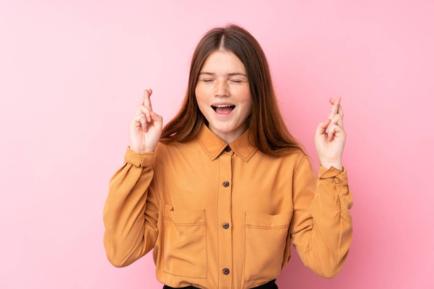 Menina adolescente ucraniana sobre isolado fundo rosa com dedos cruzando
 - Foto, Imagem