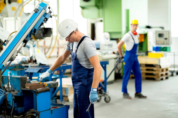 worker in protective clothing in factory using machine - Foto, Bild