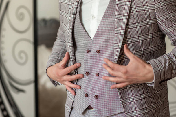 Geschäftsmann im grauen Anzug und weißem Hemd. Der Bräutigam geht auf eine Hochzeit, zieht eine Jacke an und spannt die Ärmel auf. Klassische Businesskleidung für Arbeit oder Büro. - Foto, Bild