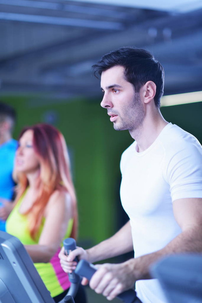 Handsome man running on the treadmill in modern gym - Valokuva, kuva