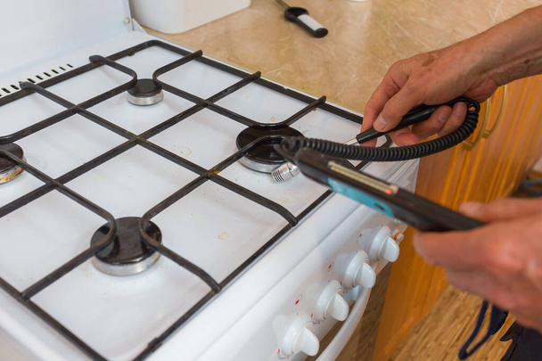 a gas safety specialist checks a gas stove in an apartment of a residential building for leaks of household gas using a measuring device a propane analyzer - Foto, Bild