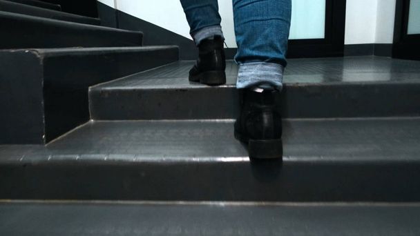 Close-up de pés escalando escadaria. Conceito. Belos pés em botas de couro e jeans subir escadas no quarto. Mulher sobe rapidamente escadas no edifício
 - Foto, Imagem