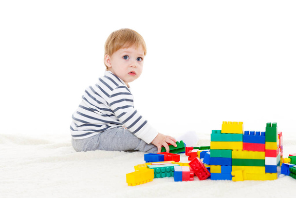 Little sweet boy plays with children blocks set on a white background. Early development and learning toys. - Foto, immagini