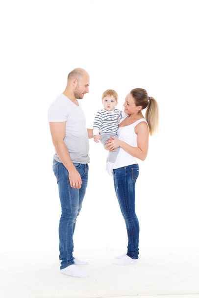 Young parents with their  sweet  child stand on a white background. Happy family. - Foto, Imagen