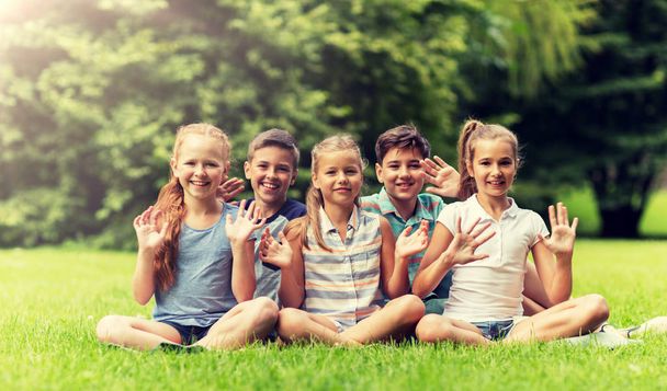 group of happy kids waving hands outdoors - Фото, зображення