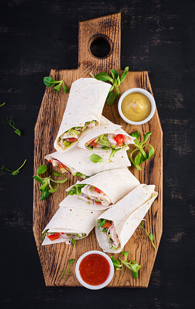 Fresh tortilla wraps with chicken and fresh vegetables on wooden board. Chicken burrito. Mexican food. Healthy food concept. Mexican cuisine.Top view, overhead - Photo, Image