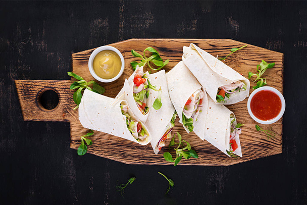 Fresh tortilla wraps with chicken and fresh vegetables on wooden board. Chicken burrito. Mexican food. Healthy food concept. Mexican cuisine.Top view, overhead - Foto, Imagen