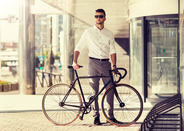 young man parking his bicycle on city street - Fotoğraf, Görsel