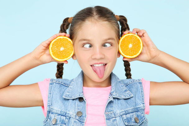 Young girl with orange fruit on blue background - 写真・画像