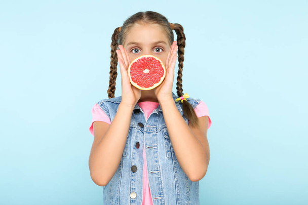 Young girl with grapefruit on blue background - Фото, изображение