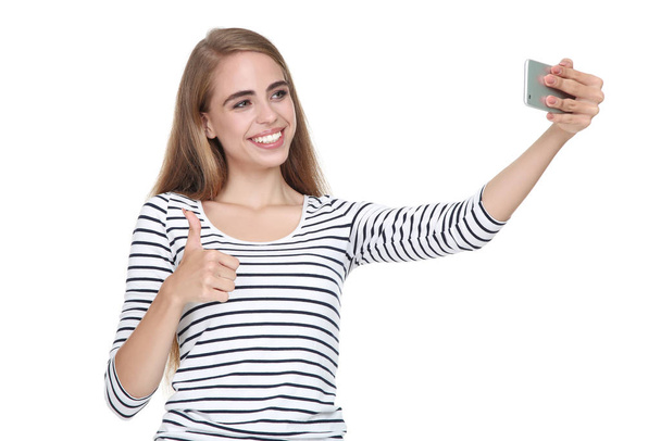 Young beautiful girl showing thumb up and making selfie on smart - Fotoğraf, Görsel
