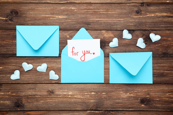Blue paper envelopes with hearts and text For You on brown woode - Foto, imagen