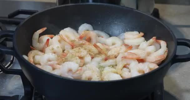 Une femme poivron et brasse les crevettes frites dans une casserole avec du beurre et de l'ail
. - Séquence, vidéo
