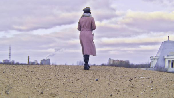 Close-up of woman in autumn boots walking on sand. Stock footage. Beautiful young woman walks along beach sand on cloudy autumn day - Photo, Image