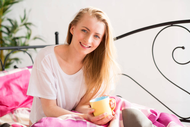blonde young woman enjoying a cup of coffee in bed - Zdjęcie, obraz