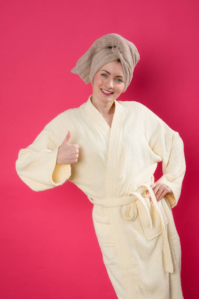 pretty woman in a bathrobe showing thumbs up - Foto, Imagen