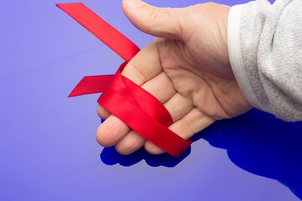 red ribbon in the hand of an adult person - 写真・画像