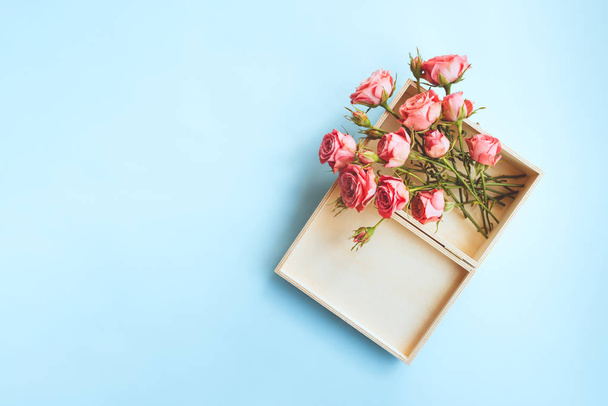 Top view of a fresh pink roses in a wooden box on blue background with copy space. Valentines day banner - Fotó, kép