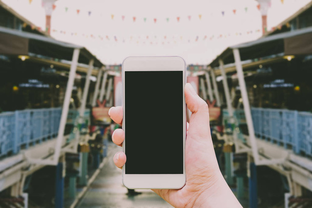 Hand hält Attrappe weißes Handy mit leerem schwarzen Bildschirm, dass Aufnahmen der Retro-Markt auf dem Hintergrund verschwommen ist. - Foto, Bild