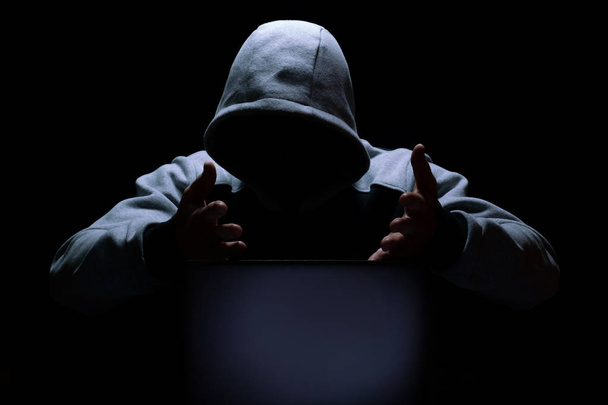 A computer hacker, in perplexity, waves his hands in front of a laptop screen - Fotoğraf, Görsel