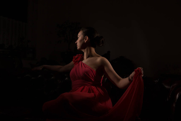 Lady in red in a dark room. - Foto, afbeelding