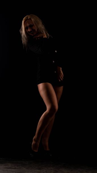 Sexy vrouw in zwart shirt poseren in donkere studio  - Foto, afbeelding