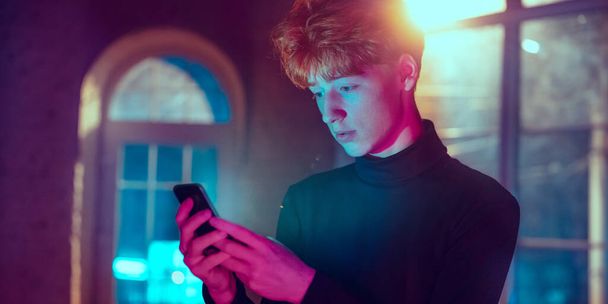 Cinematic portrait of handsome young man in neon lighted interior - 写真・画像