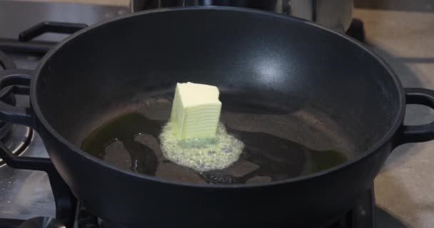A hot frying pan on which a woman puts a cube of butter and it melts and flows. - Footage, Video