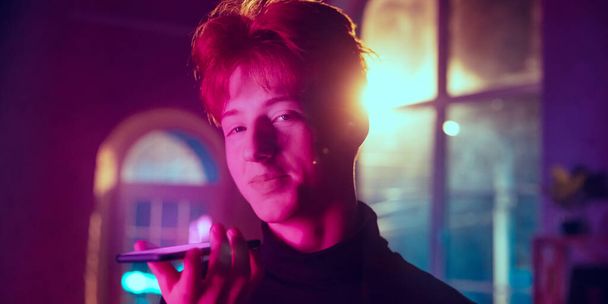 Cinematic portrait of handsome young man in neon lighted interior - Фото, изображение