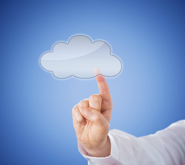 Copy space in transparent cloud computing icon which is being activated by touch. Hand in close up stretching its index finger to reach the cloud button. Light blue background. Technology metaphor. - Photo, Image