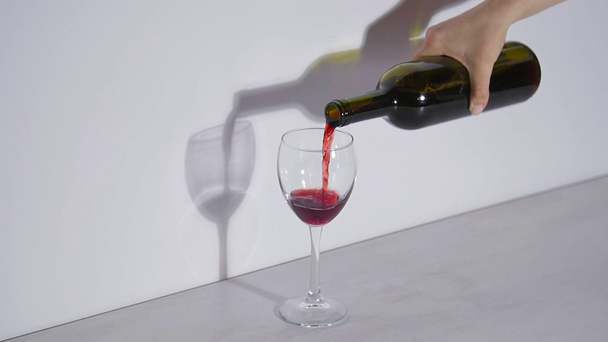 Conceptual shot, pouring red wine into a glass on a gray background - Video