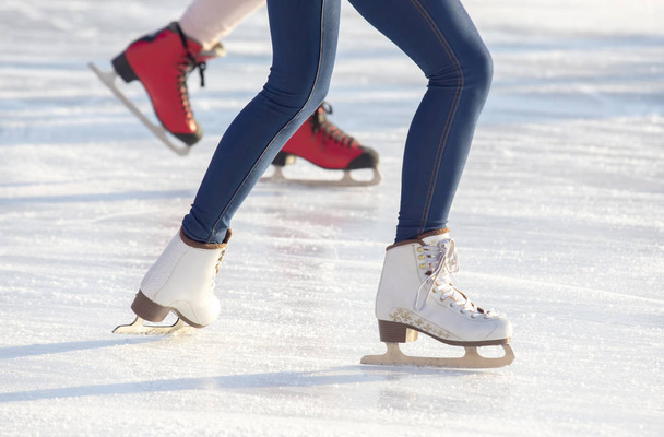 pernas de uma menina em jeans azuis e patins brancos em uma pista de gelo. ho
 - Foto, Imagem