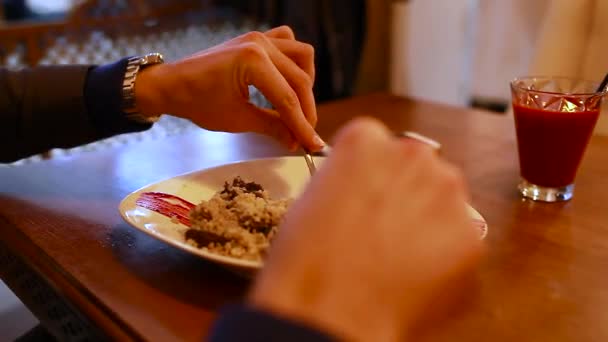 Bulgur met rundvlees, kerstomaten en olijven. Man eet schotel geserveerd in restaurant op houten tafel. Gezond eten - Video