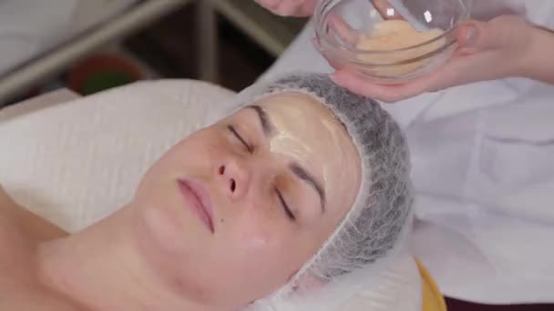 Cosmétologue professionnelle femme met un masque sur le visage du patient
. - Séquence, vidéo