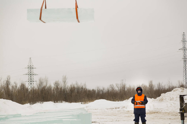 Slinger en casco naranja en el envío de bloques de hielo
 - Foto, imagen
