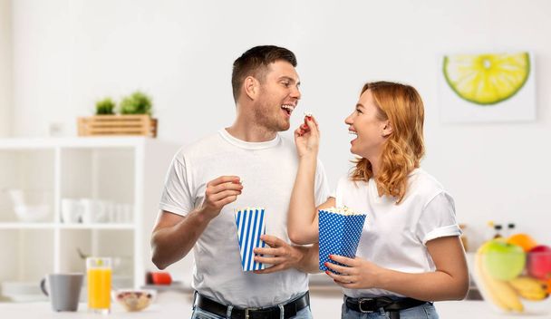 happy couple in white t-shirts eating popcorn - Zdjęcie, obraz