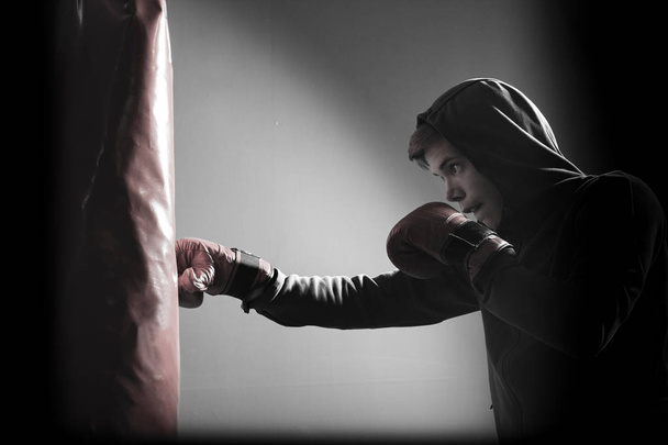 The young man workout a kick on the punching bag  - Zdjęcie, obraz