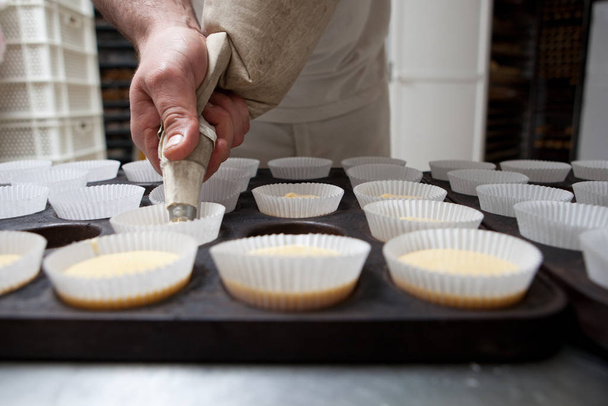 Baking cups being piped. Handmade manufacturing process of spanish madeleines - Photo, Image