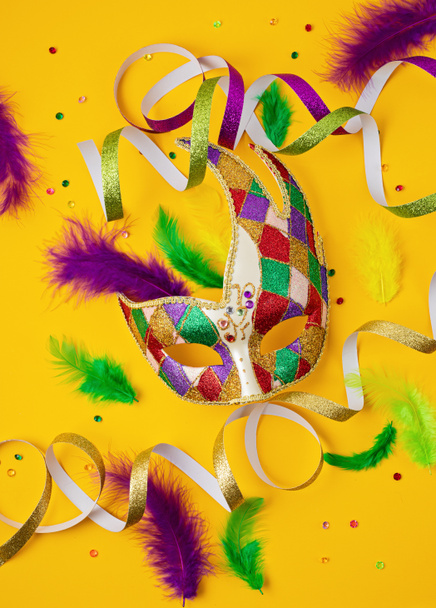 Slavnostní, barevné mardi gras nebo masožravá maska a doplňky přes žluté pozadí. Pozvánka na večírek, přání na uvítanou, benátská slavnostní koncepce. Byt ležel, horní pohled, kopírovací prostor - Fotografie, Obrázek