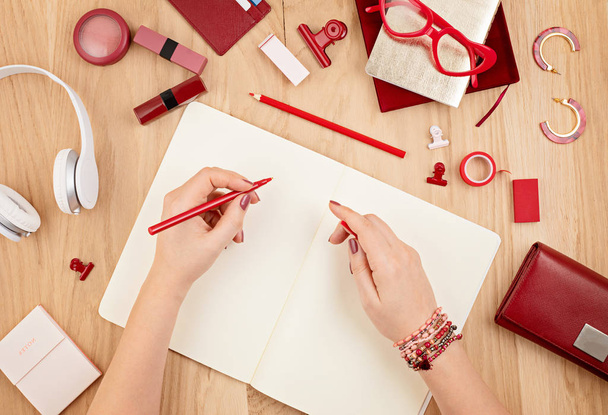 Mallintaa vasenkätinen nainen kirjallisesti tyhjä muistikirja ja punainen toimisto paikallaan. Litteä, ylhäältä päin. Päiväkirjan suunnittelu, piirtäminen, muistiinpanojen tekeminen. Luovuus, kotitoimiston käsite
 - Valokuva, kuva