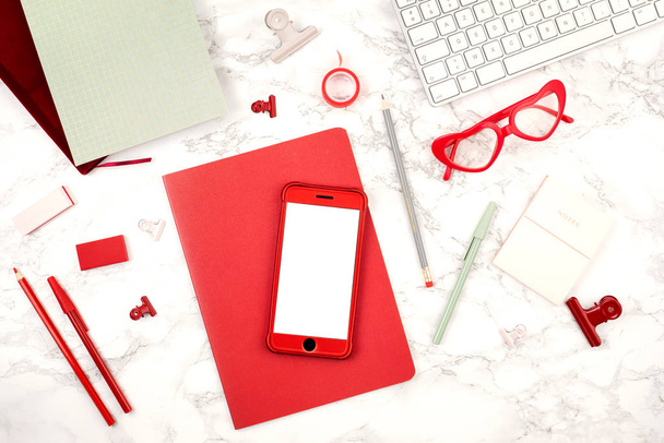 Top view of desktop with red office stationary, smart phone and keyboard. Mockup with copy space. Flat lay. Office space, home office concept - Photo, Image