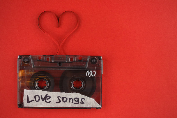 vintage old film music cassette on a trendy red background with the inscription love song, background music, music lovers, heart - Valokuva, kuva