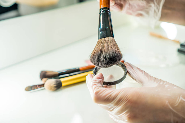 Makeup brush in artist hand near the makeup table - Fotografie, Obrázek