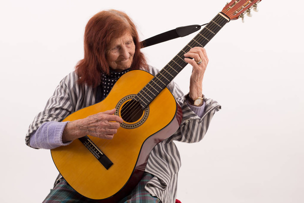 Funny elderly lady plays passionate on a classic acoustic guitar - Foto, Imagen